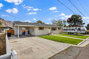Single story home featuring driveway, an attached carport, a front yard, and brick siding