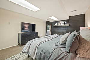 Carpeted bedroom featuring wood walls and a fireplace
