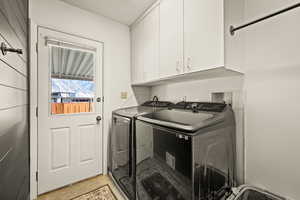 Laundry area featuring independent washer and dryer, cabinet space, and light tile patterned floors