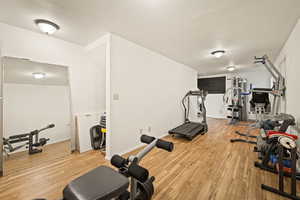 Exercise area with light wood-style floors and a textured ceiling