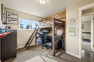 Bedroom featuring light carpet, a textured ceiling, and a desk