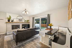 Living room with a textured ceiling, a fireplace, wood finished floors, and a chandelier