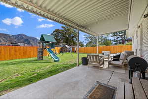 Fenced backyard with outdoor lounge area, a patio area, a grill, a playground, and a mountain view