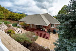 Back of house with roof with shingles, a wooden deck, and brick siding