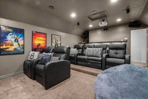 Home theater featuring vaulted ceiling, carpet, recessed lighting, and a textured ceiling