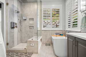 Bathroom featuring a freestanding tub, healthy amount of natural light, a stall shower, and tile walls