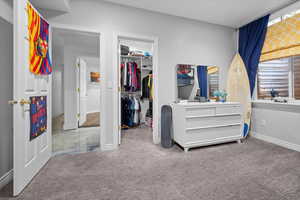 Carpeted bedroom featuring baseboards and a walk in closet