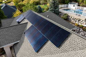 Exterior view of a shingled roof and a fenced backyard