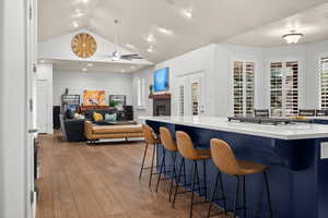 Bar area featuring a fireplace, blue cabinets, light wood finished floors, recessed lighting, and light stone counters