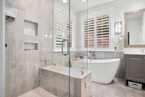 Bathroom featuring a stall shower, a soaking tub, vanity, tile walls, and recessed lighting
