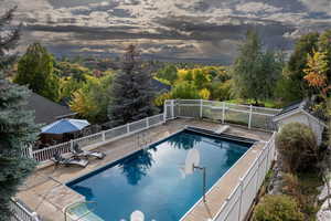 View of swimming pool with a patio area and view of scattered trees