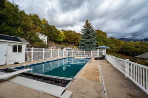 View of swimming pool featuring a diving board, a fenced backyard, and a patio area