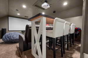 Carpeted cinema featuring a textured ceiling, vaulted ceiling, and recessed lighting