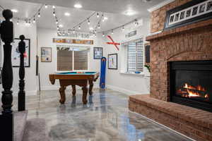 Recreation room featuring billiards, a textured ceiling, and a brick fireplace