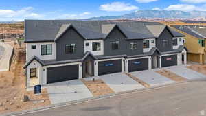 Modern inspired farmhouse featuring a mountain view, stucco siding, driveway, and an attached garage