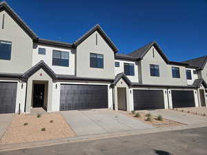 Modern farmhouse featuring concrete driveway, stucco siding, an attached garage, and a tile roof