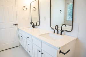 Bathroom featuring double vanity, light tile patterned floors, and decorative backsplash
