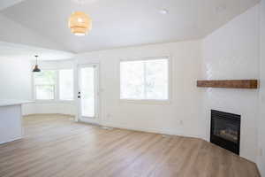 Unfurnished living room featuring plenty of natural light, light wood-style flooring, a large fireplace, recessed lighting, and lofted ceiling