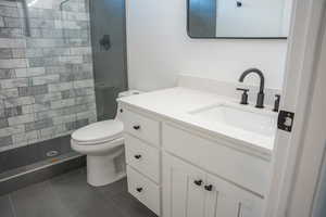 Bathroom featuring vanity, a shower stall, and dark tile patterned flooring