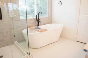 Full bath featuring tile patterned flooring, a freestanding bath, and a stall shower