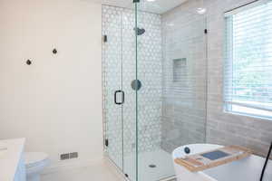 Bathroom with tile patterned floors, a stall shower, a freestanding tub, and vanity