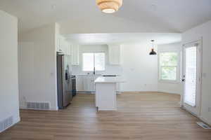 Kitchen with a center island, white cabinets, light countertops, appliances with stainless steel finishes, and light wood-style flooring