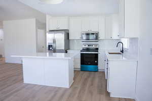 Kitchen with appliances with stainless steel finishes, white cabinets, and decorative backsplash