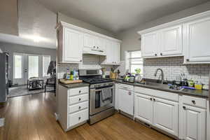 Kitchen with stainless steel appliances, white cabinetry, a textured ceiling, and dark wood finished floors