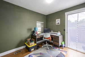 Home office featuring wood finished floors, a textured ceiling, and a textured wall