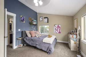 Carpeted bedroom with vaulted ceiling and ceiling fan