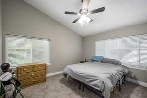 Bedroom featuring vaulted ceiling, light carpet, multiple windows, and a ceiling fan