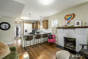Kitchen featuring a breakfast bar area, a peninsula, dark countertops, brown cabinets, and a textured ceiling