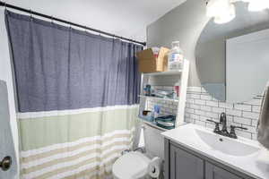 Bathroom with vanity, tile walls, curtained shower, tasteful backsplash, and a textured wall