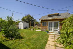 View of yard featuring french doors, a vegetable garden, and a storage unit