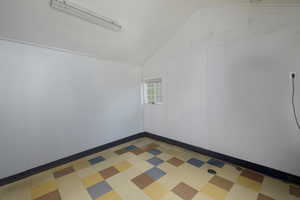 Empty room featuring vaulted ceiling and light flooring