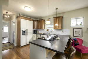 Kitchen with dark countertops, dark wood-style flooring, a kitchen bar, a peninsula, and paneled fridge