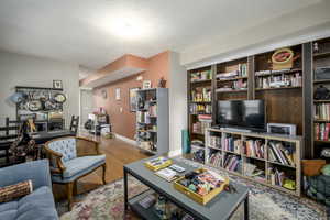Living room featuring light wood finished floors, a textured ceiling, and an office area