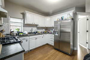 Kitchen featuring dark countertops, stainless steel fridge with ice dispenser, white cabinetry, dark wood-type flooring, and a textured ceiling