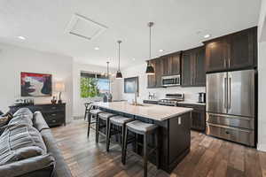Kitchen featuring open floor plan, stainless steel appliances, a breakfast bar, an island with sink, and pendant lighting