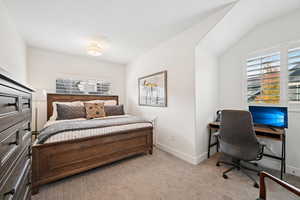 Bedroom featuring multiple windows, light colored carpet, and a desk
