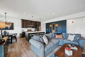 Living area featuring light wood-style flooring, recessed lighting, a chandelier, and attic access