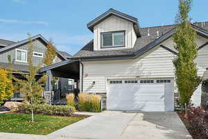 Craftsman-style house featuring covered porch, driveway, a shingled roof, and a garage