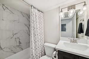 Full bath featuring shower / bath combo, a textured ceiling, vanity, and electric panel