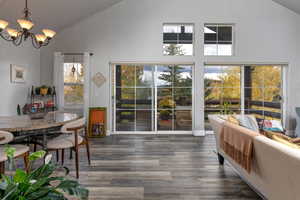 Dining area with high vaulted ceiling, wood finished floors, and a chandelier