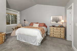 Existing decor. Carpeted primary bedroom with vaulted ceiling