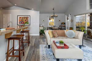 Living room featuring wood finished floors, a chandelier, recessed lighting, and high vaulted ceiling