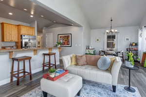 Living room with vaulted ceiling, dark wood-style floors, a chandelier, and recessed lighting