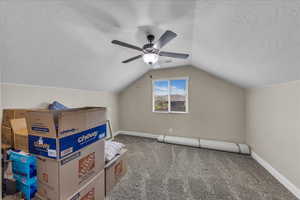 Additional living space with carpet, vaulted ceiling, a textured ceiling, and a ceiling fan