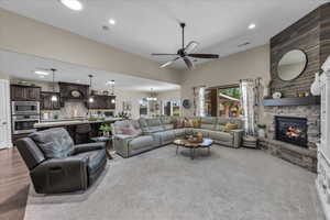 Living room featuring a chandelier, a stone fireplace, recessed lighting, and ceiling fan