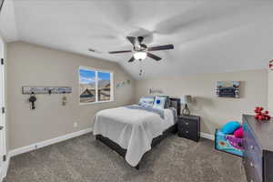 Carpeted bedroom featuring lofted ceiling, ceiling fan, and a textured ceiling
